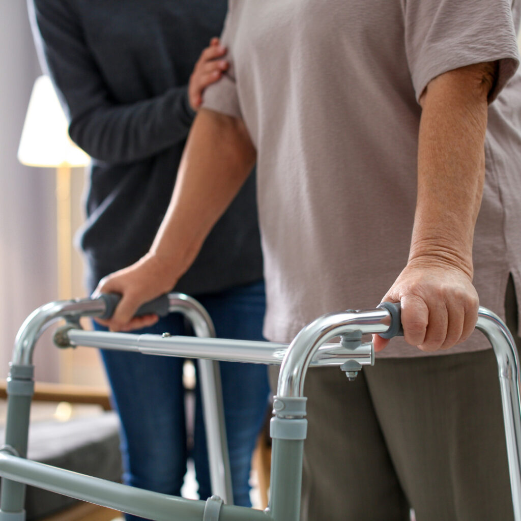 Someone holding the arm of an older person using a walker