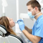 A dentist conducts an oral exam on a patient