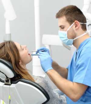 A dentist conducts an oral exam on a patient