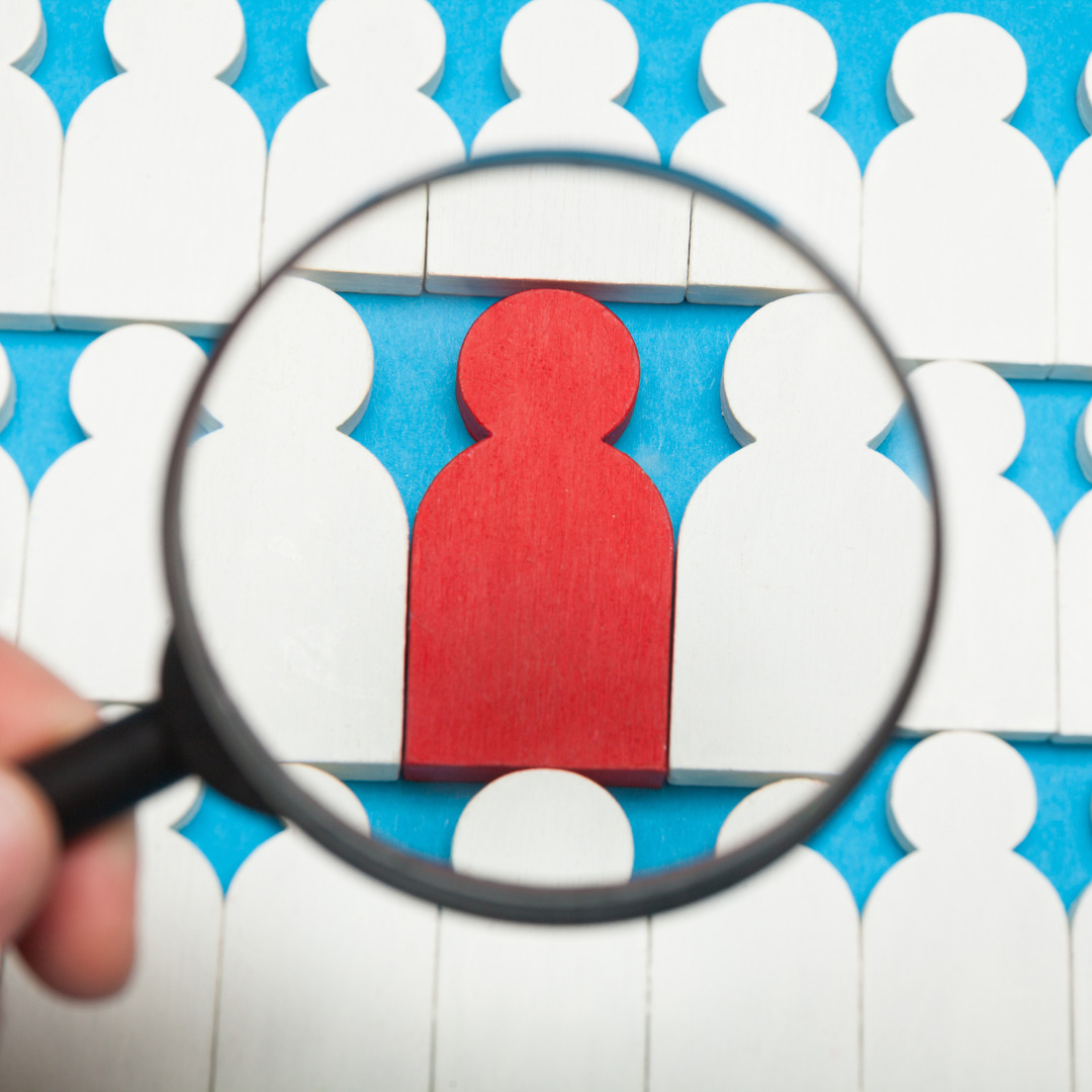 A magnifying glass identifying a red paper cutout of a silhouette