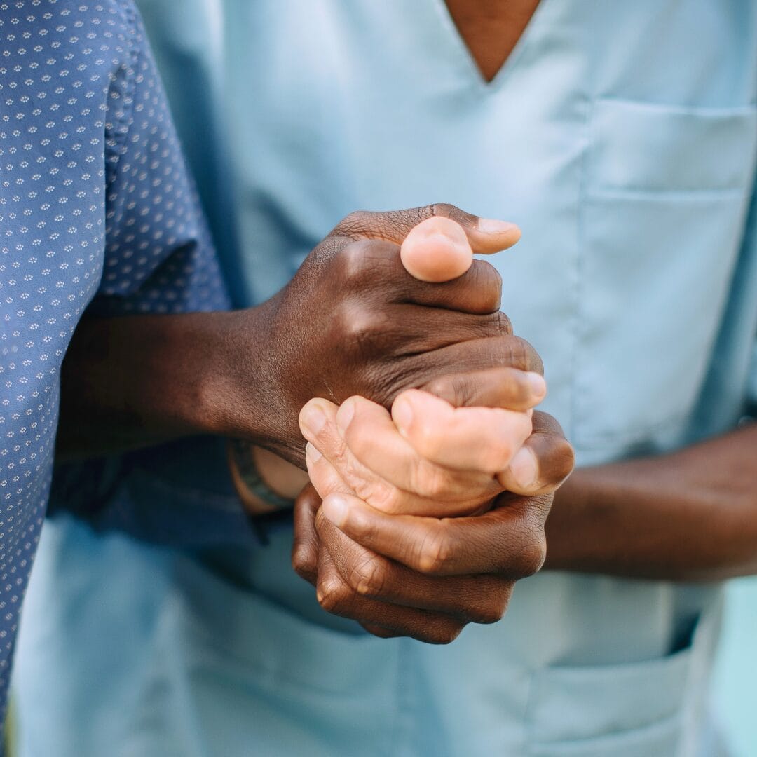 A nurse practitioner holds the hand of a patient for a featured image for the Nurse Practitioner (NP) Job Outlook blog